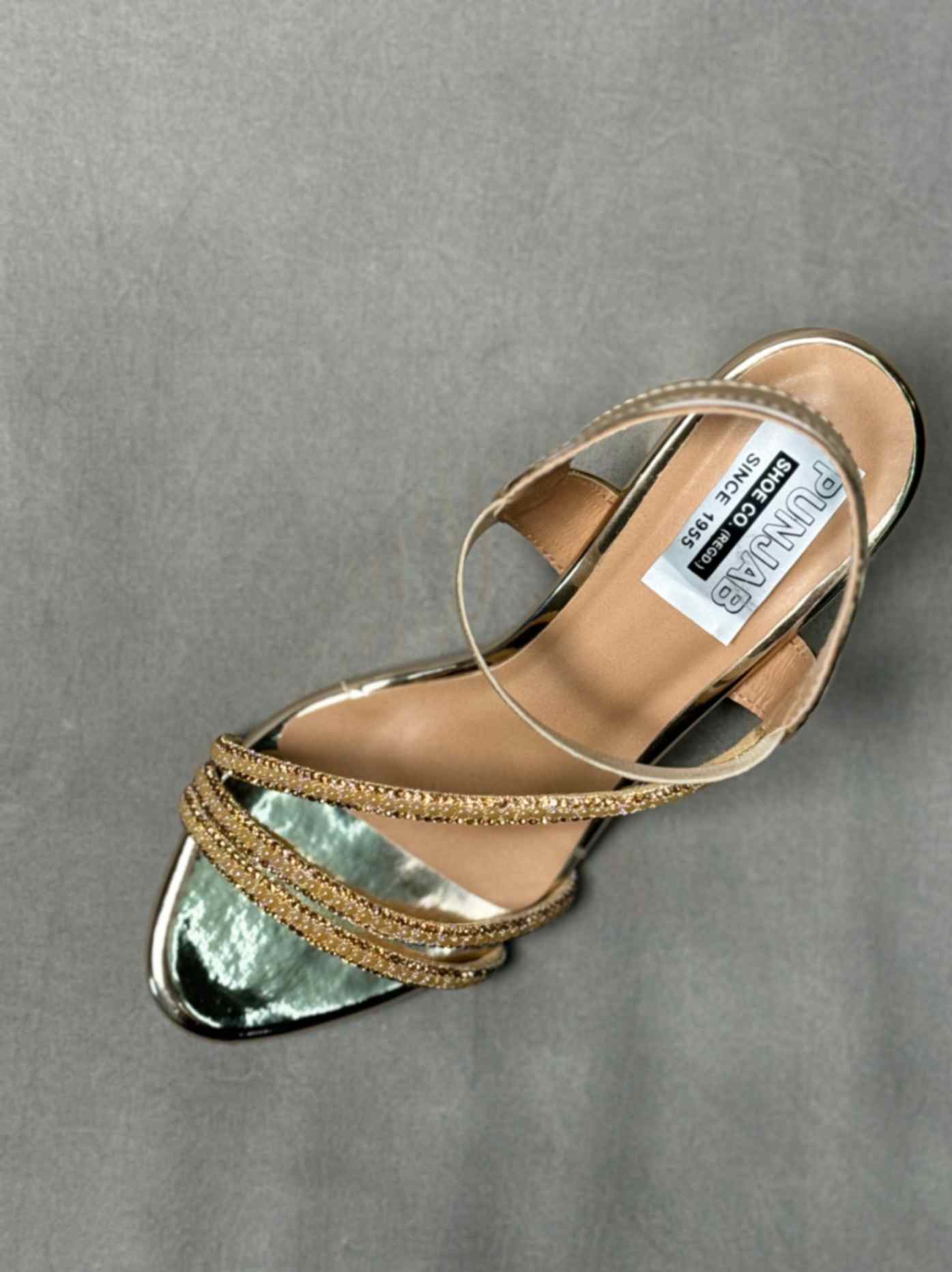 Top view of golden ankle strap heels with glittery accents and a pointed toe, showcasing a luxurious and elegant design.