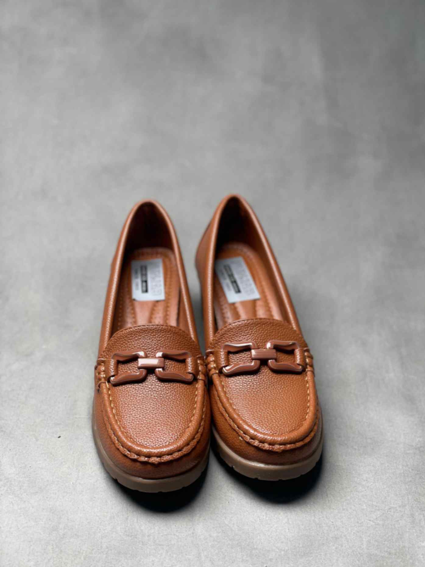 Top view of brown heeled loafers with buckle, showcasing detailed stitching and a cushioned insole for added comfort.
