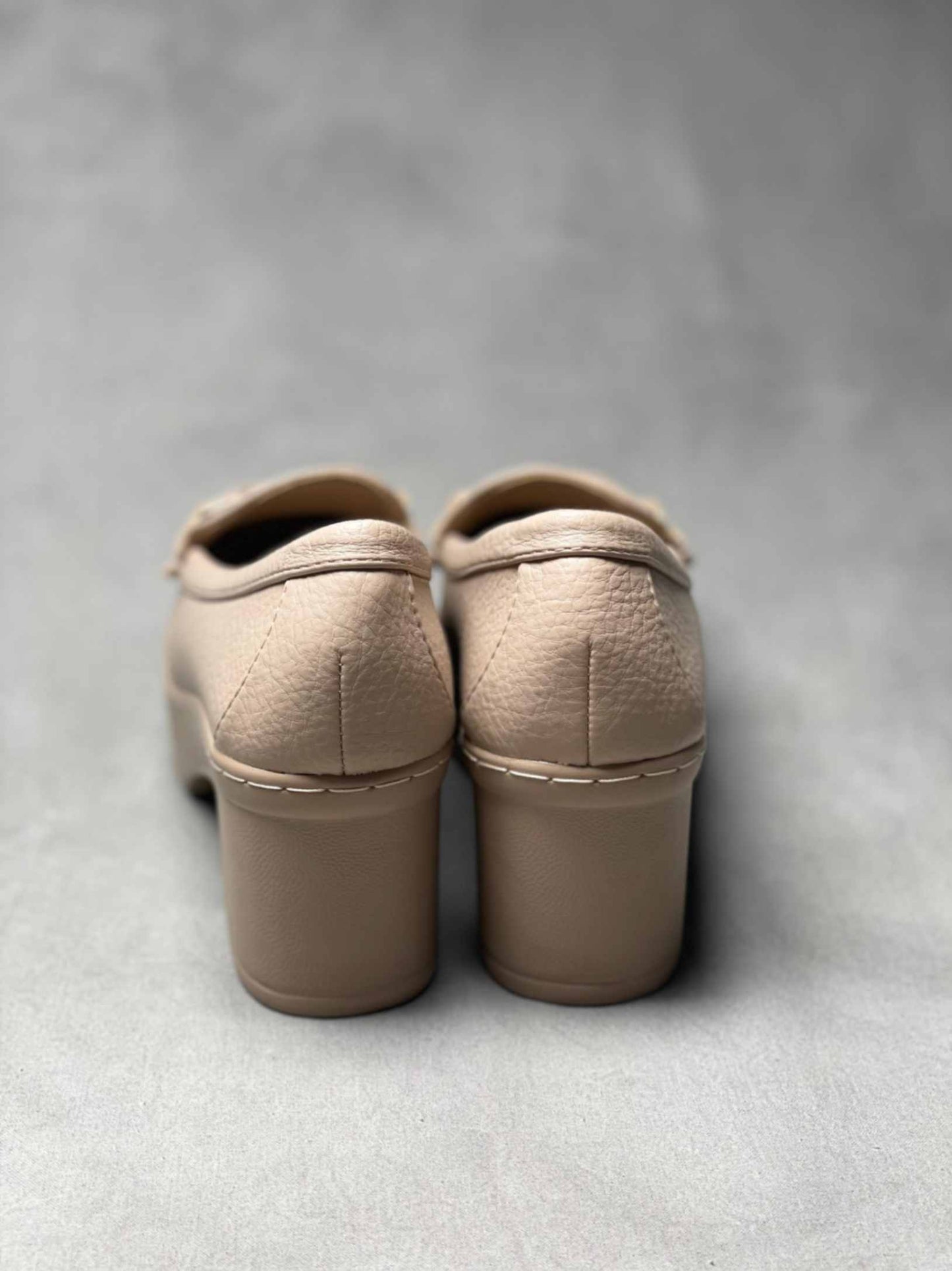 Rear view of beige heeled loafers with buckle, highlighting the block heel and seamless stitching for a polished look.