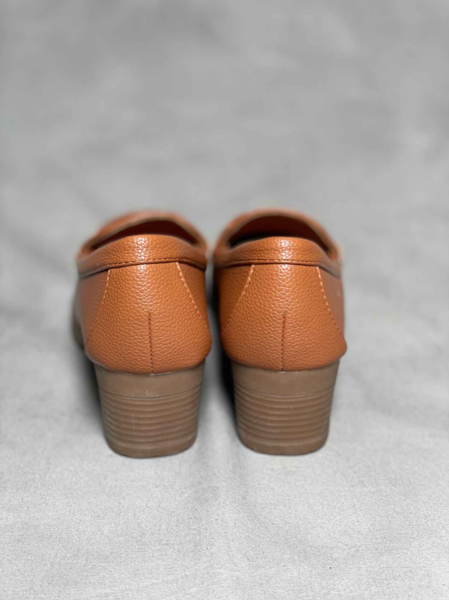 Rear view of brown heeled loafers with buckle, highlighting the block heel and seamless stitching for a polished look