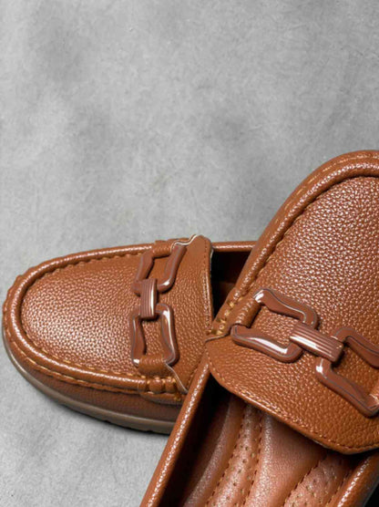 Close-up of brown heeled loafers with buckle, emphasizing the textured material and elegant buckle detail on the upper.