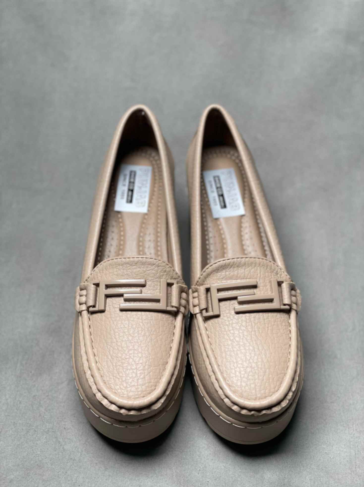 Top view of beige heeled loafers with buckle, showcasing detailed stitching and a cushioned insole for added comfort.