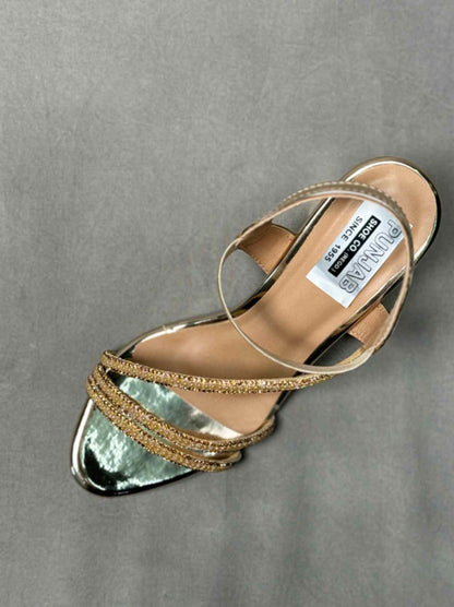 Top view of golden ankle strap heels with glittery accents and a pointed toe, showcasing a luxurious and elegant design.